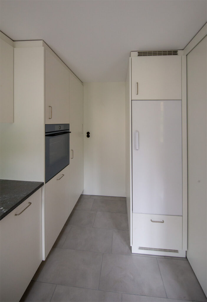 Moderne Einbauküche mit weißen Hochglanzfronten und integrierten Geräten